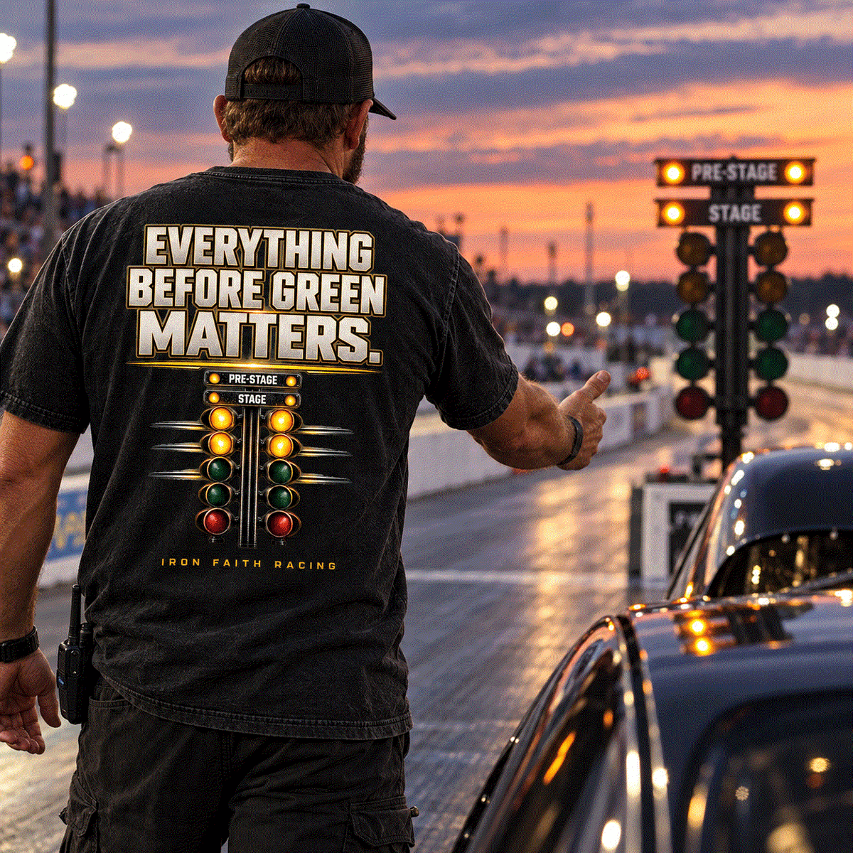 Man in Everything Before Green Matters Tee in the staging lane facing the start tree at dusk