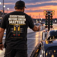 Man in Everything Before Green Matters Tee in the staging lane facing the start tree at dusk