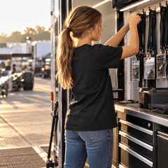 Girl in black youth tee reaching into a tool cabinet in the race trailer