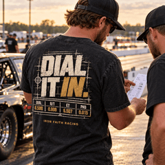 Drag racer wearing Dial It In Tee checking a time slip beside his car at the strip