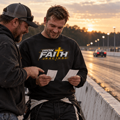 Two racers reviewing time slips by the track wall, one in logo crewneck
