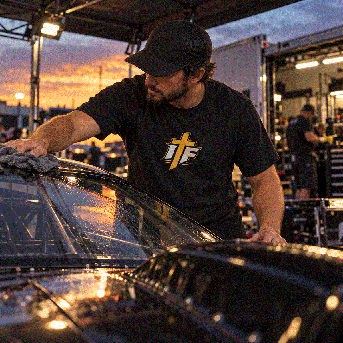 Man in IFR Icon Tee wiping down a drag car in the pit at dusk