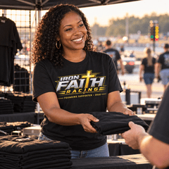 Smiling woman in Founding Supporter Tee handing over a shirt at a trackside merch booth