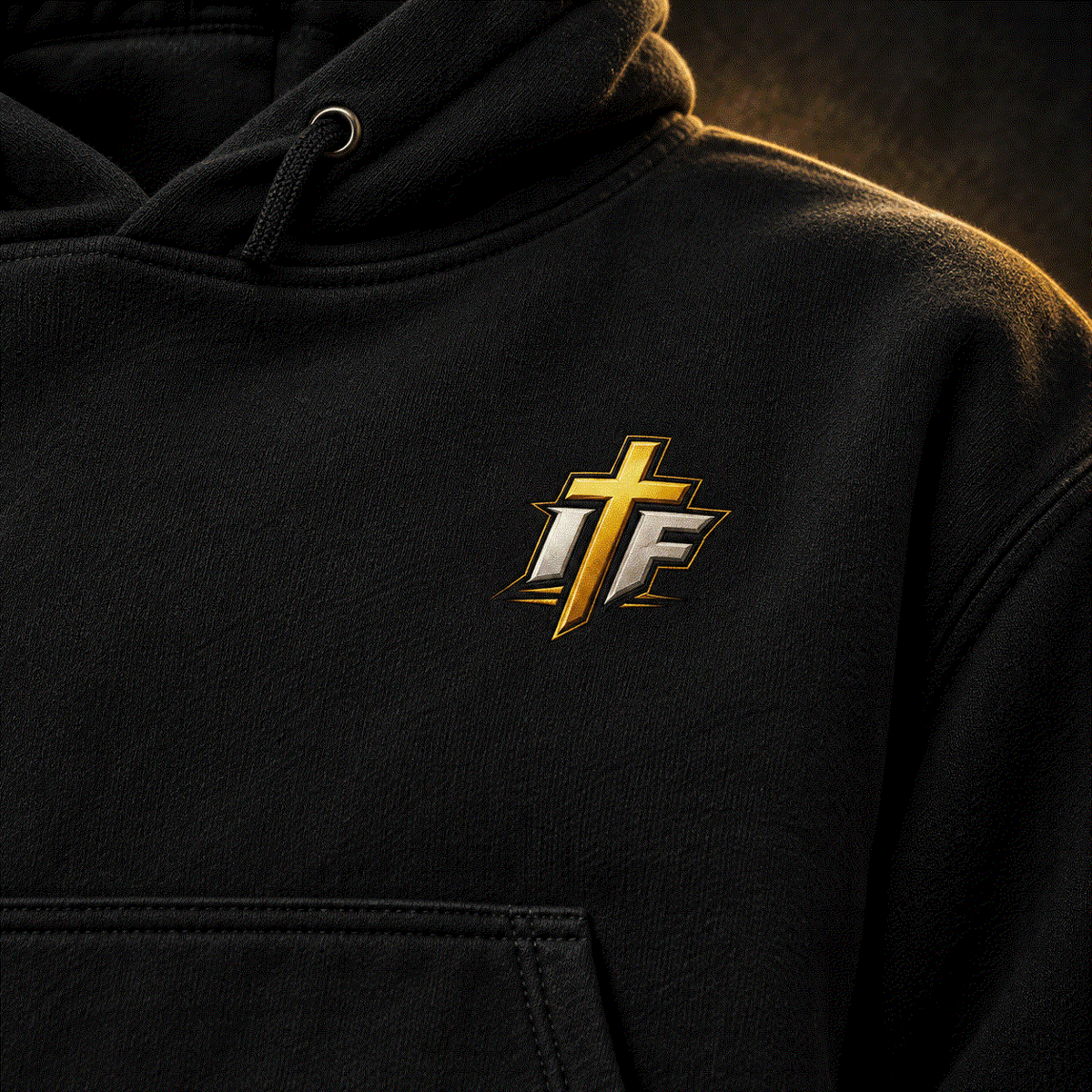 Close-up of gold IFR cross logo on black Faith Hoodie chest
