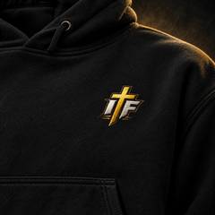Close-up of gold IFR cross logo on black Faith Hoodie chest