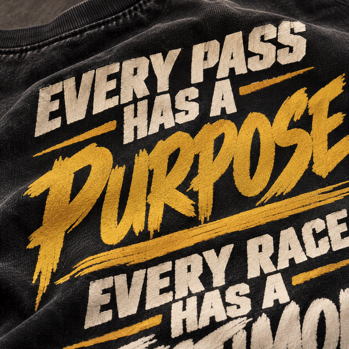 Close-up of gold Every Pass Has a Purpose back print on washed black cotton