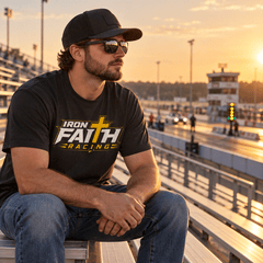Man in Iron Faith Racing logo tee and cap seated in the grandstands at golden hour