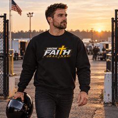 Man in Iron Faith Racing logo crewneck carrying a helmet in the pits at dawn