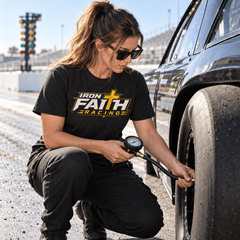 Woman in Iron Faith Racing logo tee checking tire pressure on a drag car