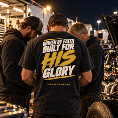 Pit crew huddled at night, one wearing the For His Glory Tee