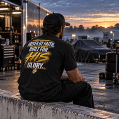 Man in Faith Tee seated on a wall in the paddock before dawn