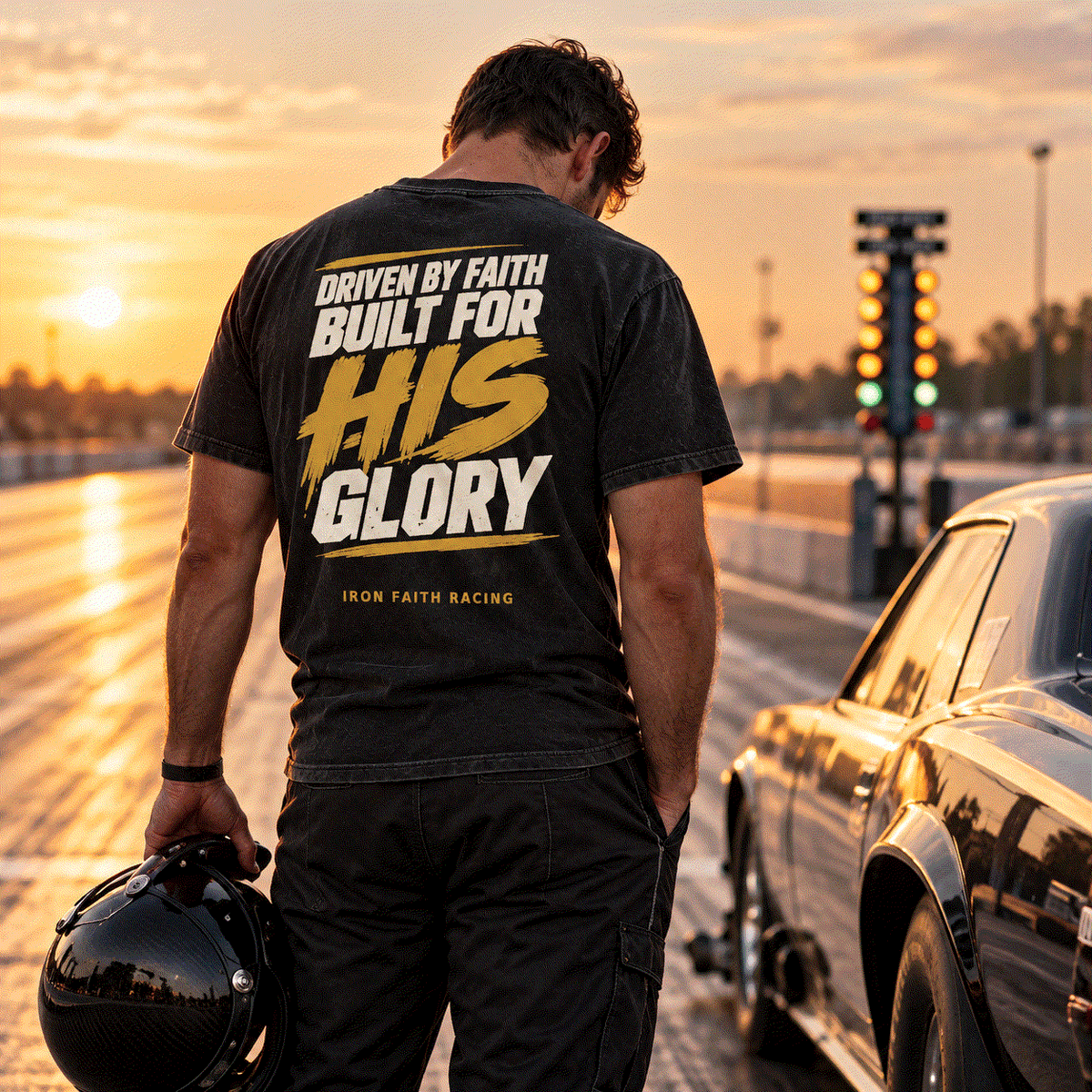 Driver in For His Glory Tee holding a helmet in the staging lane at sunset