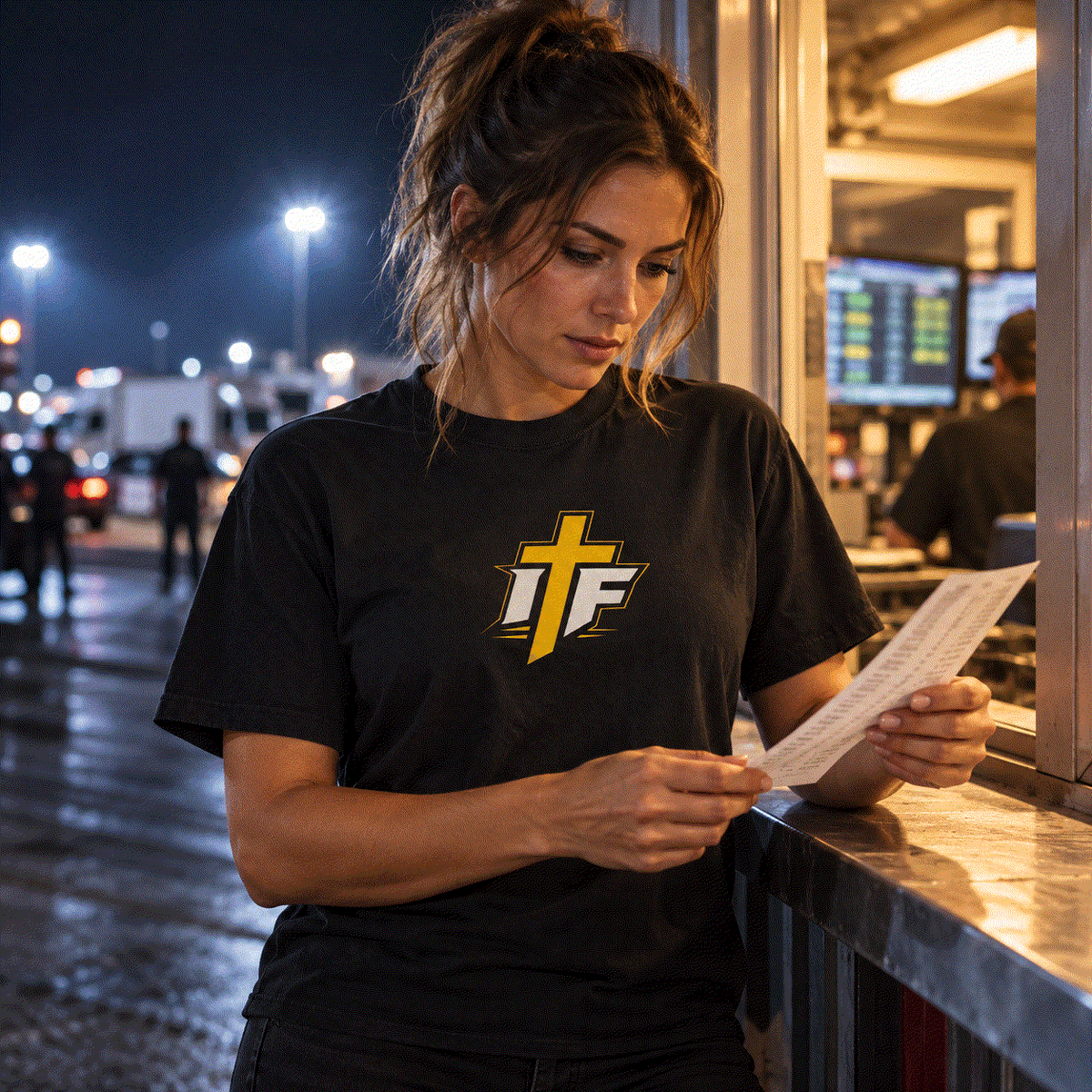 Woman in IFR Icon Tee reading a time slip at the track at night