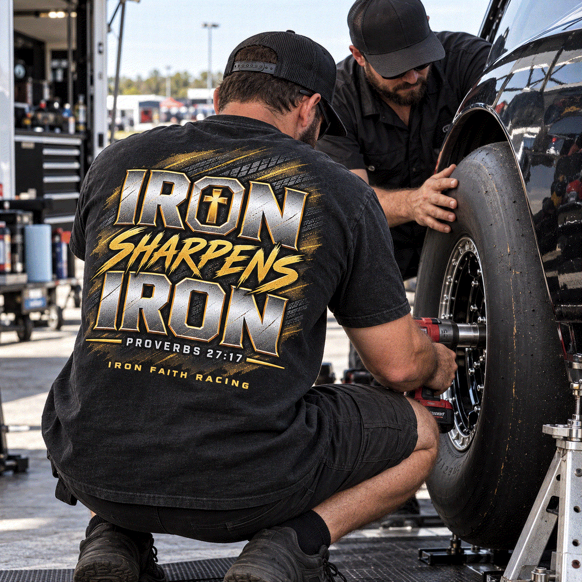Crew member in Iron Sharpens Iron Tee torquing a race wheel in the pits
