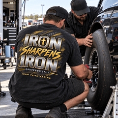 Crew member in Iron Sharpens Iron Tee torquing a race wheel in the pits