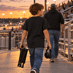 Young fan in youth icon tee walking toward the grandstands at sunset