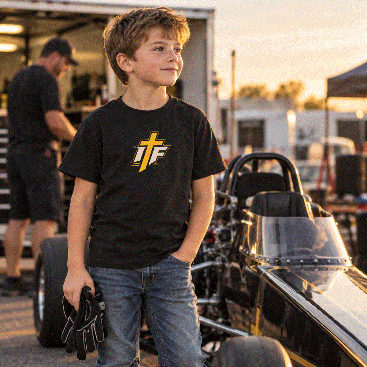 Boy in IFR youth icon tee standing by a junior dragster in the paddock